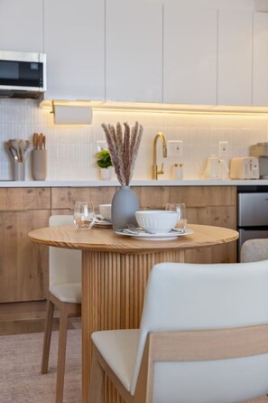 Eine moderne Küche mit einem runden Holztisch, weißen Stühlen und einer Vase mit Trockenpflanzen.