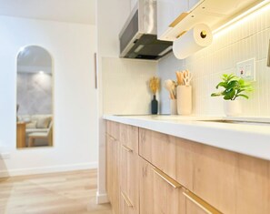 Eine moderne Küche mit Holzschränken, einer weißen Arbeitsplatte und einem eingebauten Herd.