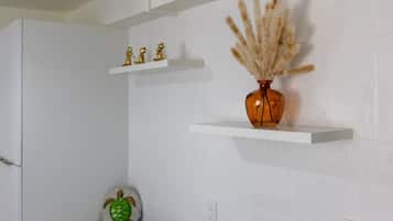 A bathroom with white tiles, a vase with dried plants, and a turtle decoration on the floor.