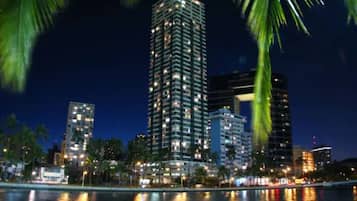 A nighttime cityscape with a prominent high-rise building reflecting on the water.
