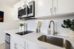 Una cocina moderna con armarios blancos, electrodomésticos de acero inoxidable y un lavamanos doble.