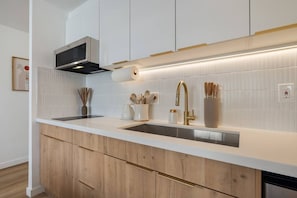 Een moderne keuken met witte kasten, roestvrijstalen apparatuur en een houten aanrecht.