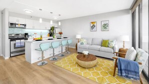 Una cocina moderna con una isla central, taburetes de bar, un sofá y una mesa de centro.