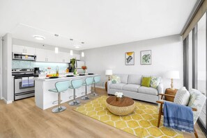 A modern kitchen with a central island, bar stools, a sofa, and a coffee table. - Waikiki Paradise w/ Ocean View & a Free Parking (Honolulu)