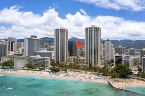 Eine Küstenstadtlandschaft mit Hochhäusern, einem Strand mit Sonnenschirmen und einem roten Positionsmarker.