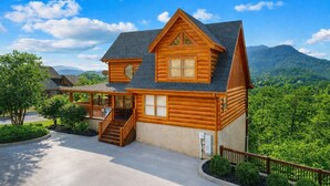 Une cabane en rondins avec un porche, un escalier et une vue sur les montagnes.