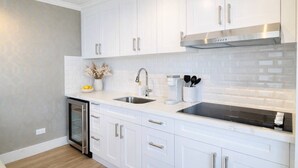 Una cocina moderna con armarios blancos, electrodomésticos de acero inoxidable y salpicadero azulejado.