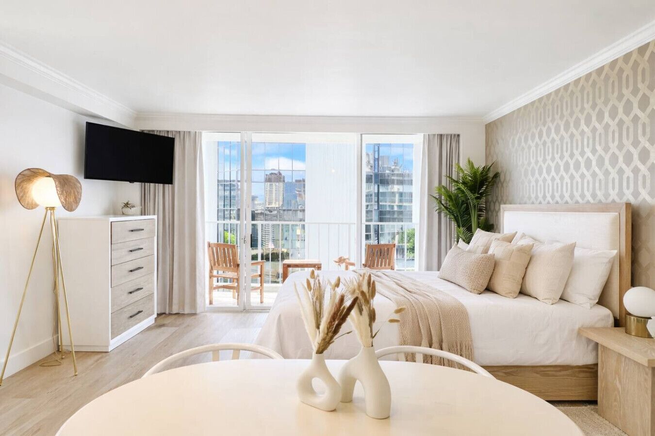 Een moderne hotelkamer met een groot bed, een bureau, een stoel, een televisie en een balkon met uitzicht over de stad.