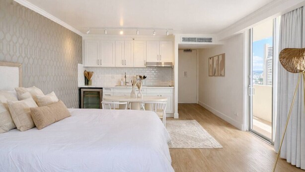 Un dormitorio con una cama grande, una kitchenette y vistas a la ciudad.