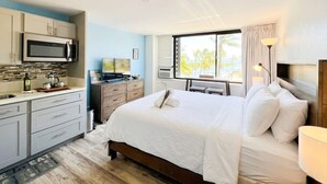 Ett hotellrum med en säng, ett skrivbord, en mikrovågsugn och ett fönster med utsikt.