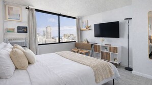 Een moderne hotelkamer met een groot bed, een bureau, een flatscreen televisie en uitzicht op de stad.