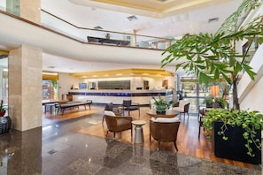 A spacious lobby with a reception desk, seating area, and a large indoor plant. - Unobstructed Ocean View Spacious Studio (Honolulu)
