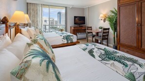 A hotel room with two beds, a desk, a TV, and a view of the city. - Unobstructed Ocean View Spacious Studio (Honolulu)