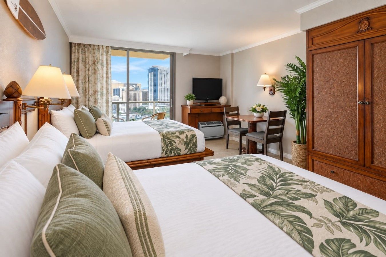 A hotel room with two beds, a desk, a television, and a large window with a city view.