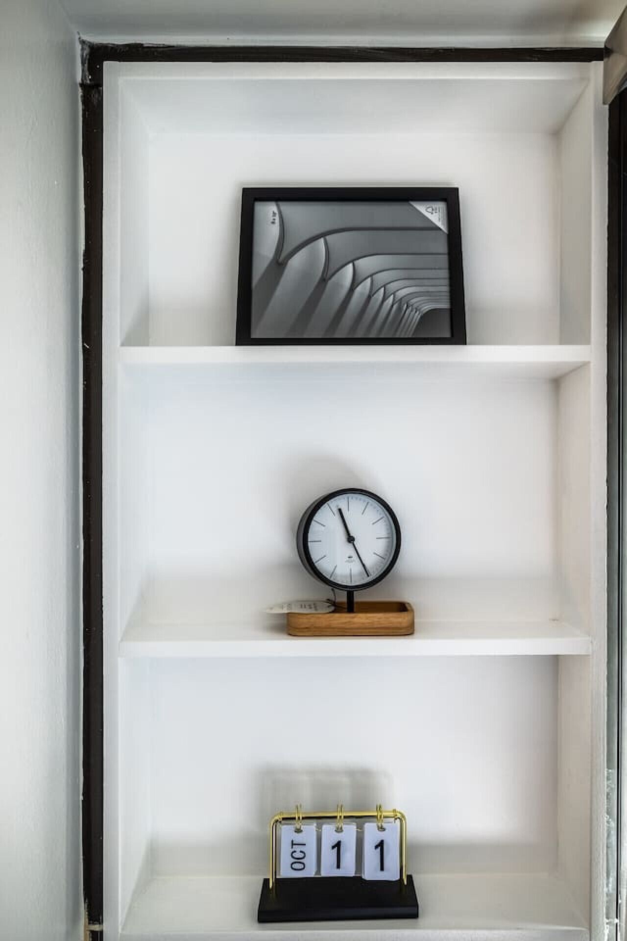 A wall-mounted shelf with a framed picture, a clock, and a calendar.