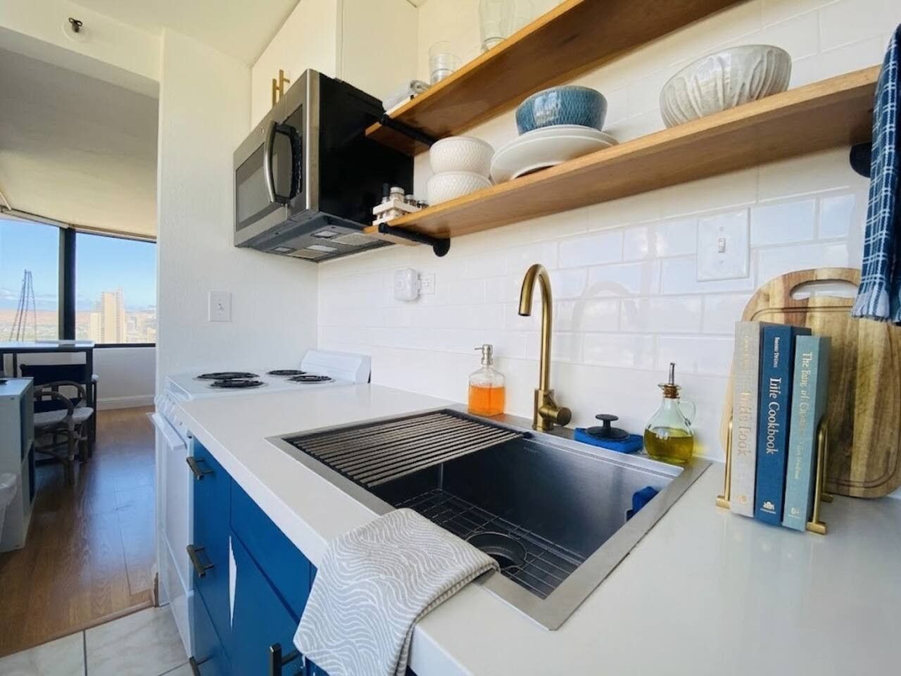 A modern kitchen with a built-in stove, a sink, and a window overlooking a cityscape.