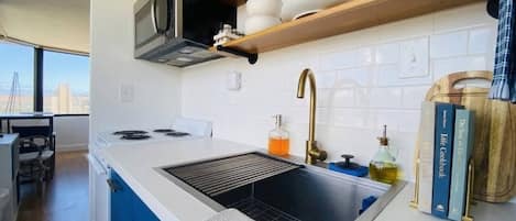 A modern kitchen with a built-in stove, a sink, and a window overlooking a cityscape.