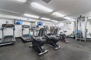 A gym with treadmills, elliptical machines, and weightlifting equipment. - Rare Waikiki Corner 31F Unit with Stunning Views (Honolulu)