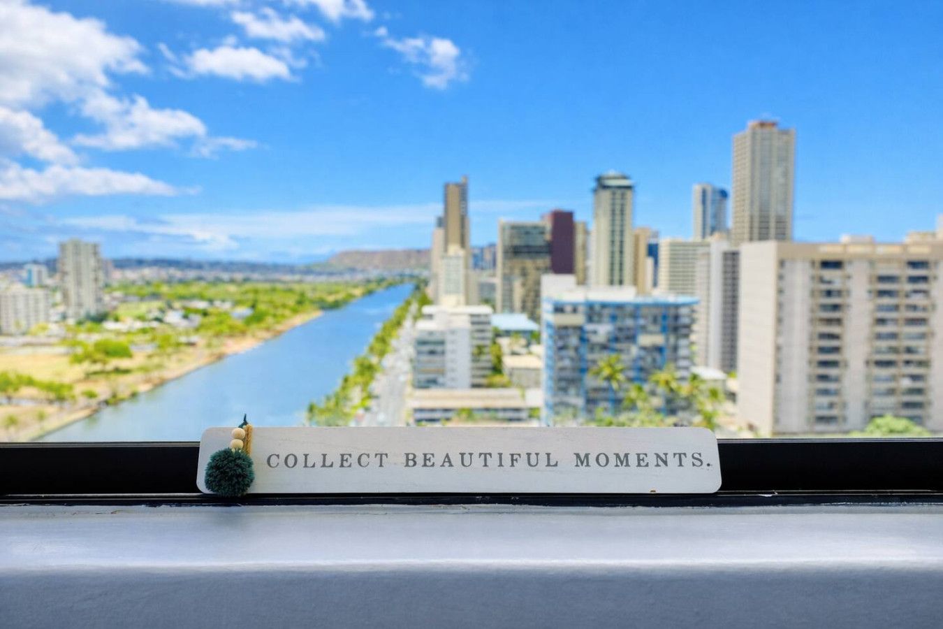 Vista de un paisaje urbano con un río, edificios y un letrero que dice 'COLLECT BEAUTIFUL MOMENTS'.