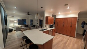 Una cocina moderna con una isla grande, armarios de madera y un comedor con sofá y sillas.