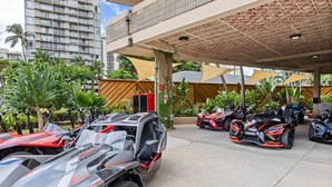Un espace de stationnement couvert où plusieurs voitures de sport performantes sont garées sous un auvent.
