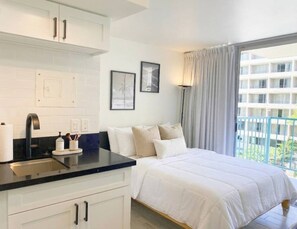 Une chambre d’hôtel avec un lit, une fenêtre avec des rideaux, un lavabo et un placard.