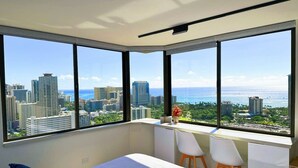 Ein Schlafzimmer mit großem Fenster, einem Bett und einem Schreibtisch mit zwei Stühlen.