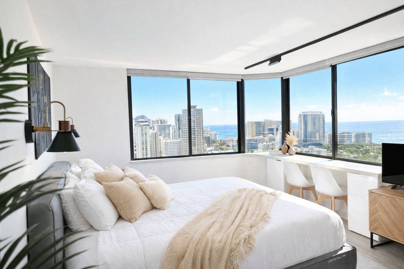 Quarto moderno com cama grande, escrivaninha e vista para o horizonte urbano.