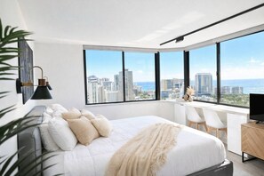 Une chambre moderne avec un grand lit, un bureau et une vue sur le paysage urbain.