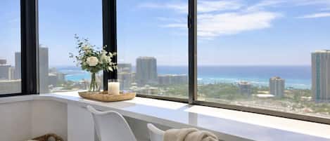 A room with a large window overlooking a cityscape and the ocean.