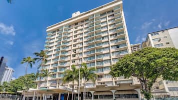 A multi-story hotel with balconies, a covered entrance, and palm trees in the foreground.