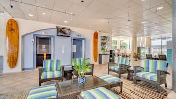 A lobby with wicker furniture, a reception desk, and surfboards on the walls.