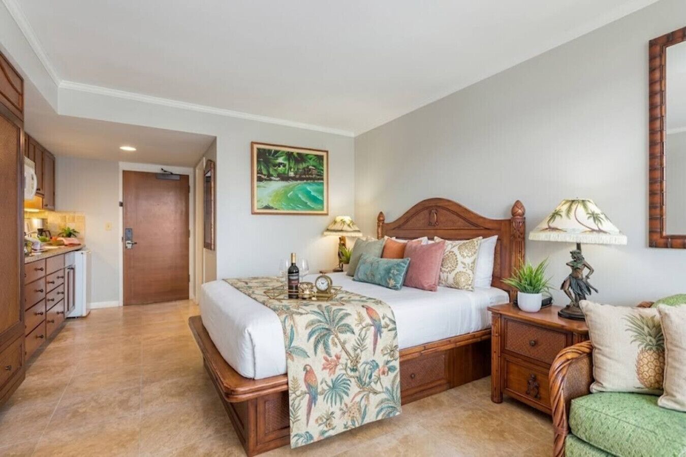 A hotel room with a wooden bed, a nightstand with a lamp, a green chair, a wooden dresser, and a painting on the wall.