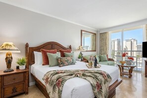 Une chambre d’hôtel avec un grand lit, une table de chevet, une petite table avec un vase, une chaise et une vue sur la ville.
