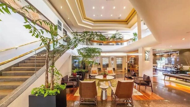 Een hotel lobby met een trap, een zithoek en een receptiebalie.