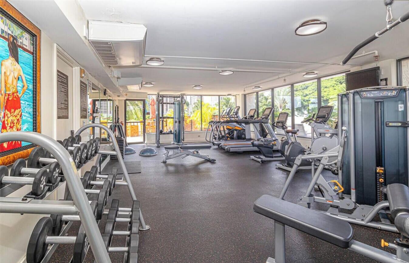 Une salle de sport équipée de tapis de course, d’appareils de musculation et d’haltères.