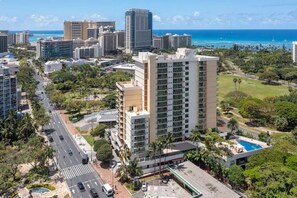 Un grand hôtel, avec de nombreux étages, entouré de verdure et offrant une vue sur l’océan.