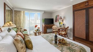 Een hotelkamer met een bed, een bureau, een televisie en uitzicht op de stad.