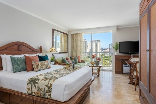 Une chambre d’hôtel avec un grand lit, une télévision, un balcon avec vue sur la ville et un coin repas.
