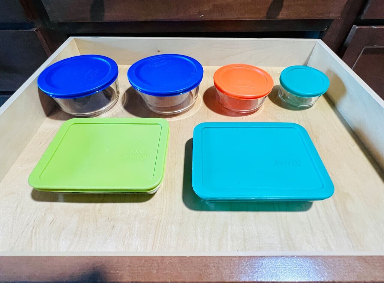 A kitchen counter with six containers of various sizes and colors.