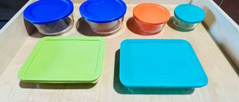 A kitchen counter with six containers of various sizes and colors.