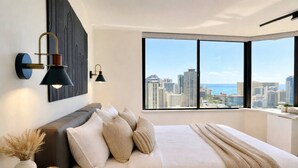 Een moderne slaapkamer met een groot bed en een stadsgezicht door het raam.