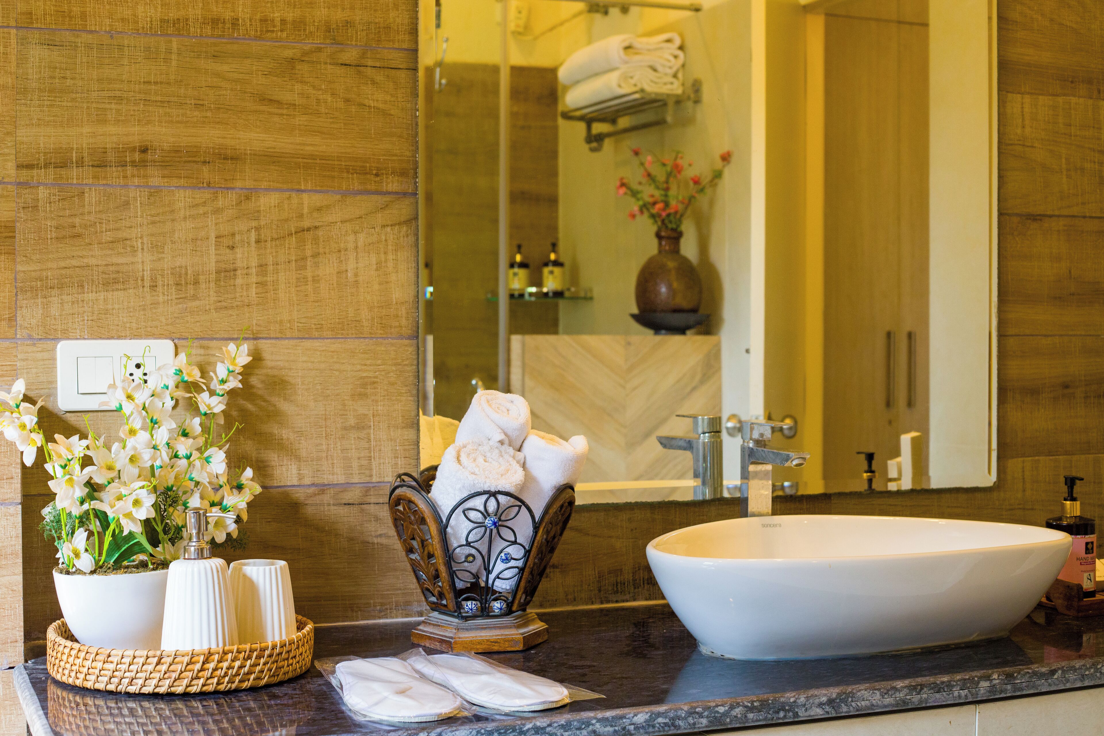 Un baño con un lavamanos grande de color blanco, un espejo y un perchero para toallas.