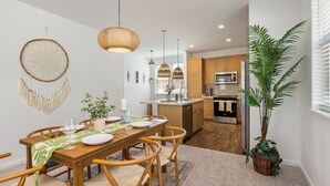 A modern kitchen with wooden cabinets, a central island, and pendant lighting. - Makaha Valley - Few Mins away to Beach (Waianae)