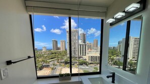 A modern bathroom with a large window, a bathtub, and a mirror. - HM15 Rare Find - Corner Ocean View Studio at Waikiki (Honolulu)