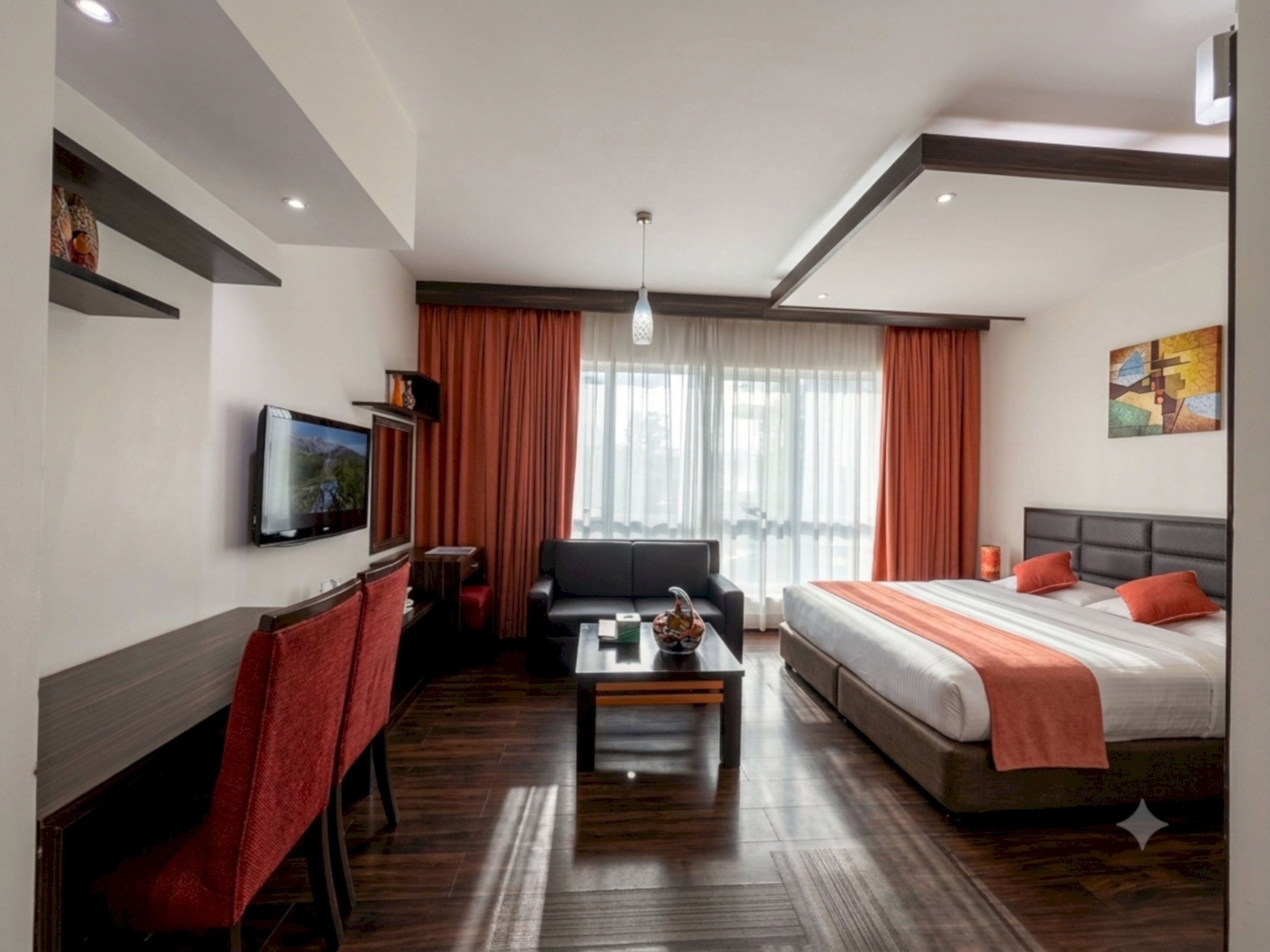 Una habitación de hotel con cama, sofá, televisión y una mesa de centro.