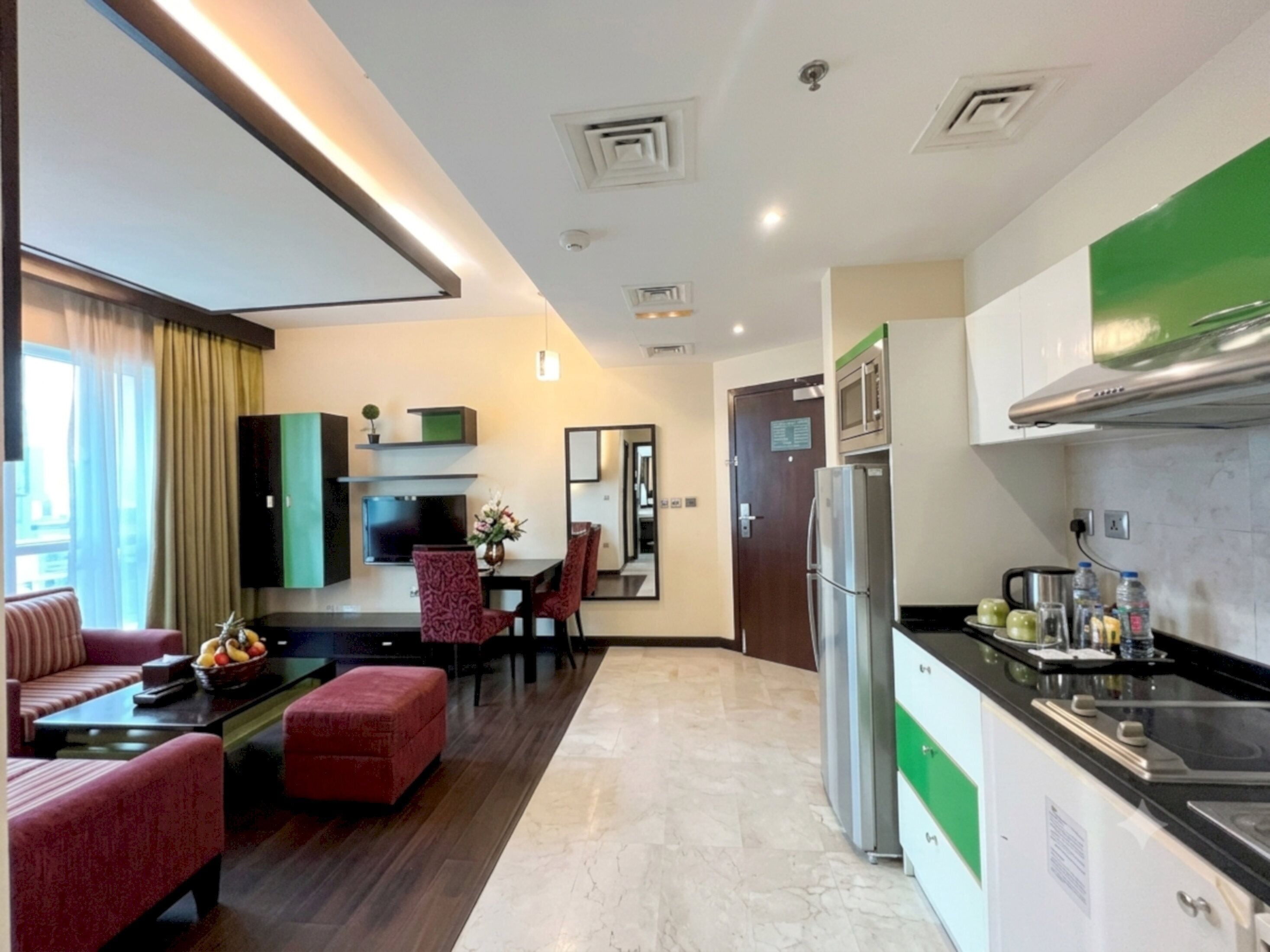 A modern hotel room with a living area, kitchenette, and a dining space.