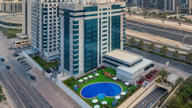 Un hotel di grandi dimensioni con piscina sul tetto, numerosi piani e vista sulla città circostante.