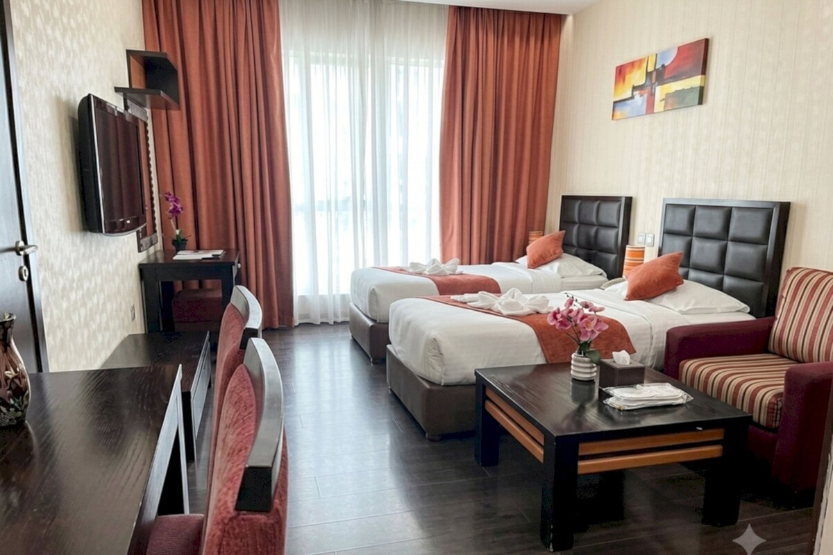 Een hotelkamer met twee bedden, een slaapbank, een eettafel en een televisie.