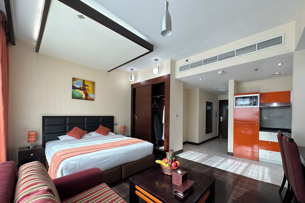 Ein Hotelzimmer mit Bett, einer Sitzecke, einem Esstisch, einer Küchenzeile und einem Flur.